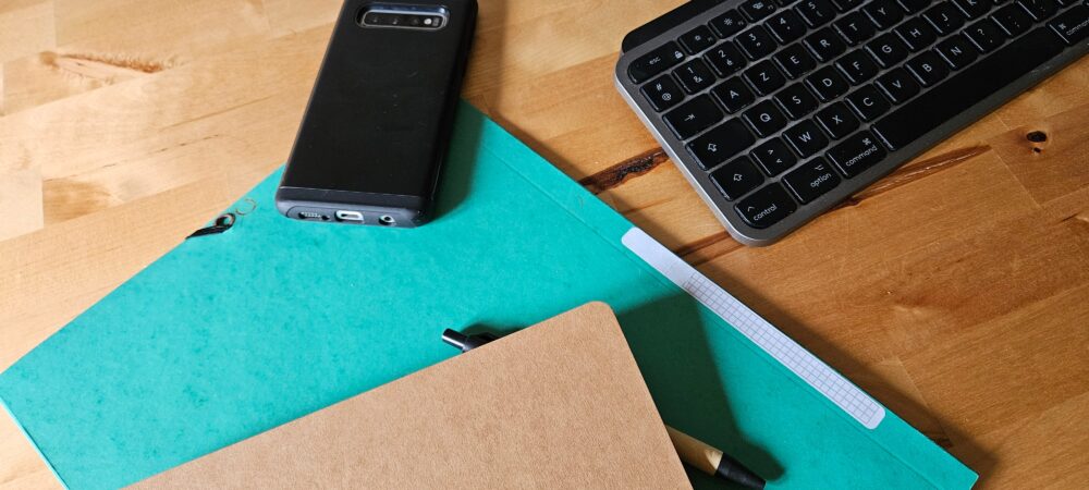 Téléphone, dossiers et clavier d'ordinateur sur un bureau en bois