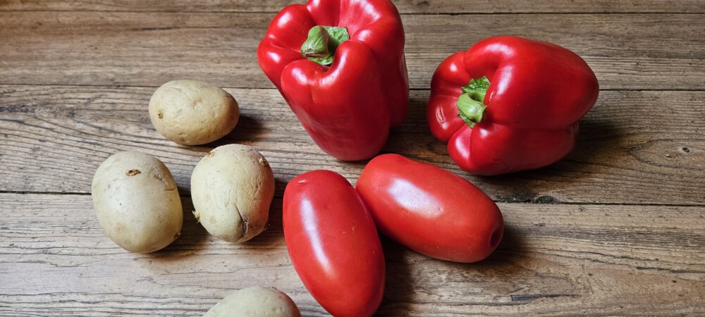 Poivrons, tomates et pommes de terre déposés sur une table en bois