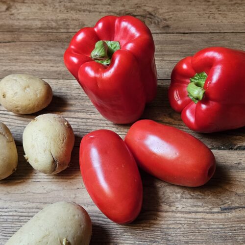 Poivrons, tomates et pommes de terre déposés sur une table en bois
