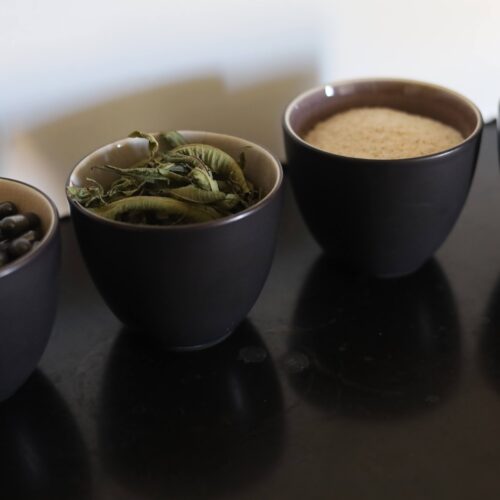 Quatre petits bols posés les uns à côté des autres, ils contienent des gélules, des feuilles de verveine séchées, du psyllium et des graines de tournesol